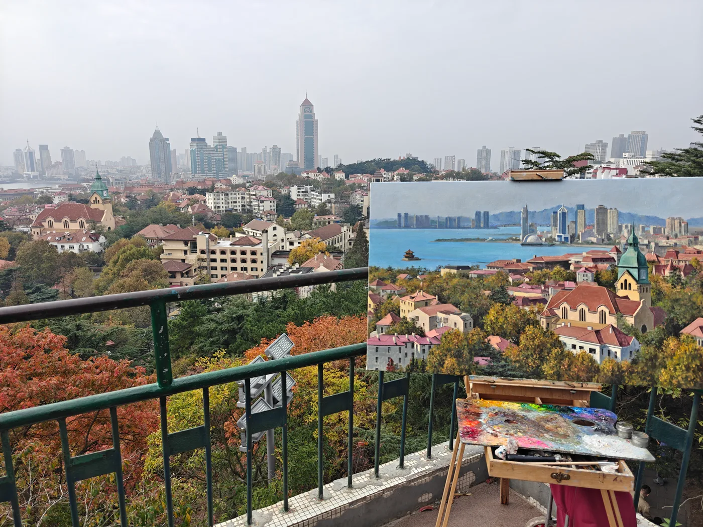 An outdoor painting on an easel overlooking the same city skyline