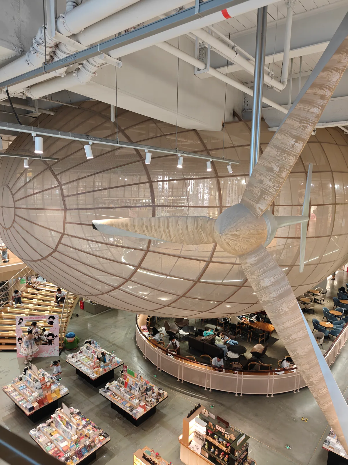 An airy bookstore with a suspended wooden aircraft above readers and books